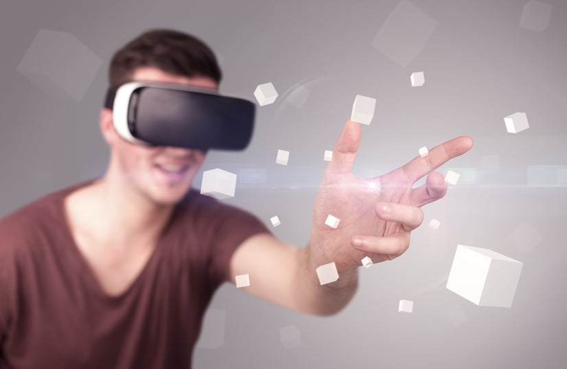 Young impressed man wearing virtual reality goggles with grey cubes around him